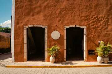 bright beautiful building wall red hot orange texture shaby. two arched entrances with doors. pots...