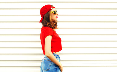 Portrait of stylish young woman wearing red baseball cap looking away on white background, blank copy space for advertising text