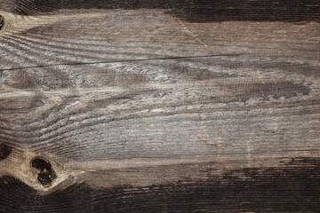 Texture of an old gray darkened board with a crack and a knot. Wooden background.