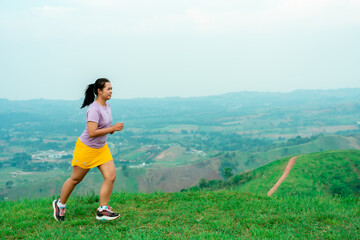 Fototapeta premium Asian trail runners, women wearing sportswear are practicing on a high mountain running. During the evening when the air is fresh atmosphere is good.