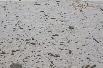 Texture of a painted white surface stained with splashes of gray cement