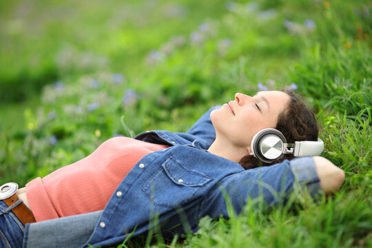 Relaxed woman lying on the grass listening to music