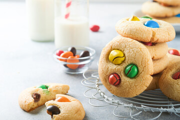 Homemade cookies with colorful chocolate candies and milk. Stack of shortbread cookies with multi colored candy on plate with bottle of milk on light gray background. Baby food concept. Copy space.