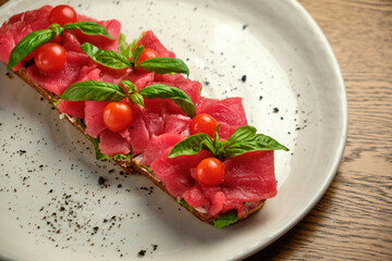 Bruschetta with red pickled meat on a white plate