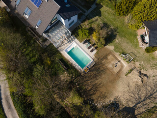 Drone flight over fresh earth area with grass grown next to pool construction site in April