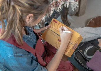 Leather start up woman writing customer name on box prepare to deliver leather products from online...