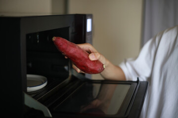 さつまいもを電子レンジで温めようとする男性