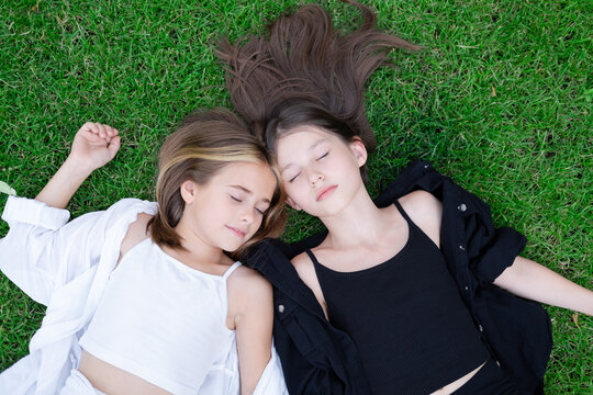 fraternal twins sisters. blonde and brunette teen girls in fashionable black and white clothes outdoors. sisterhood, siblings spending time together.