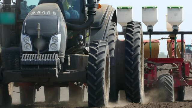 Agricultural tractor with seeder sowing and cultivating field on a beautiful sunny spring day