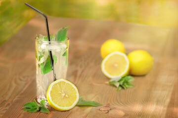 Glass with water, ice, mint leaves and lemon on a wooden surface background