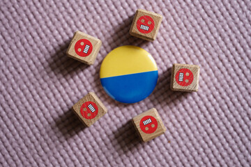 Badge with flag of Ukraine lying among evil emoticons closeup