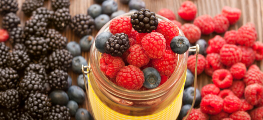 Different ripe berries set (blueberries raspberries blackberries) in a basket on a wooden table