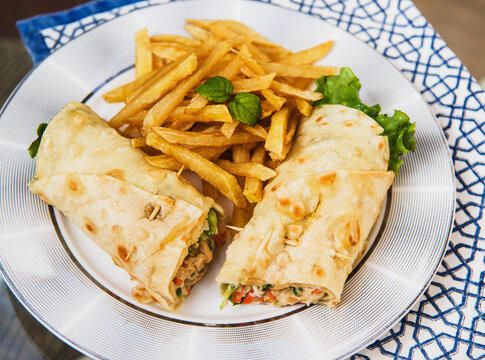 Chicken and vegetable wrap with French fries.