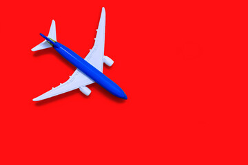 Airplane model on a red background with free space for text or advertising. Tourism or freight transport concept. Toy airplane on a yellow background with a top view