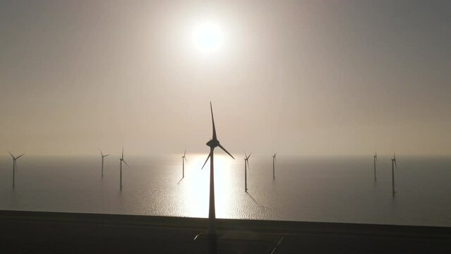 Aerial towards Wind turbines spinning on Epic Windpark on Sea with bright sunlight, Renewable Enery