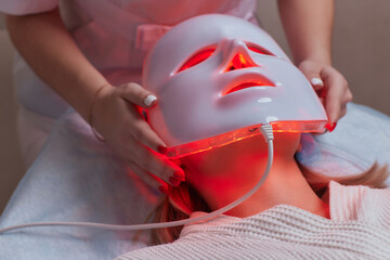 LED light anti-aging mask for facial skin care in a spa slow motion. A woman lies on a couch in a...