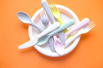colorful plastic plates, glass and cutlery on table 