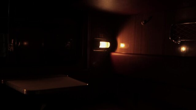 Inside compartment of corridor coach of railway passenger train at night. Light from luminaire is lit inside carriage. City lapms outside window. Empty russian railroad wagon. Travel tourism. Nobody