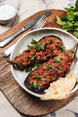 Imam bayildi. Traditional delicious Turkish food: halves of baked eggplant stuffed with vegetables on a plate. Selective focus