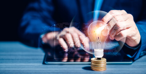 Businessman's hand touching light bulb on stacking coins. Financial and Business growth, Economic Trends, Investment ideas