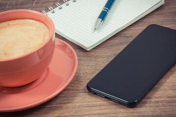 Mobile phone, coffee with milk and notepad for writing notes. Work or relaxation