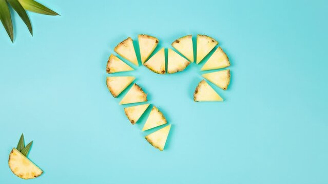 pineapple slices forming a heart on the ground on a blue background