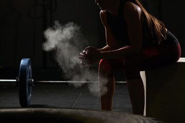Unrecognizable woman sitting down chalking her hands.