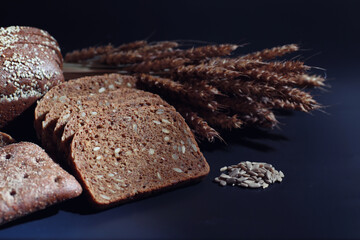 Fresh loaves of bread with wheat and gluten on a black table. Bakery and grocery concept. Fresh,...