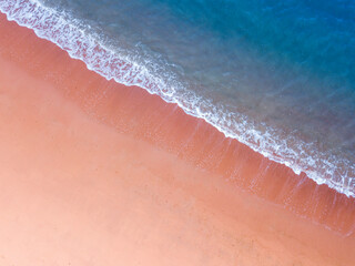Aerial view of pink sand beach with deep blue sea color and white crashing wave in summer with copy...