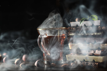 A bar of milk chocolate. Homemade milk chocolate with almonds and dried strawberries. Pieces of milk chocolate. Set of milk chocolate with tea.