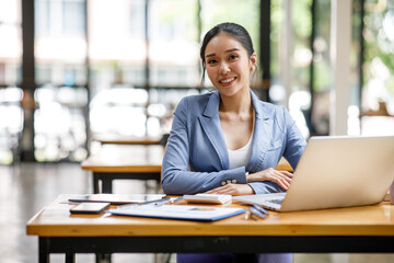 Portrait of happy Asian businesswoman looking at camera while working in office