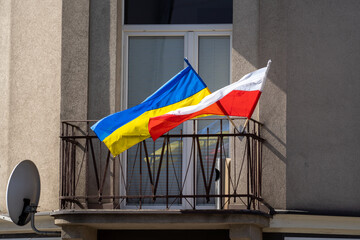 Polish and Ukrainian flags waving in the wind on the balcony of the building during the war in Ukraine, Cracow, April 2022