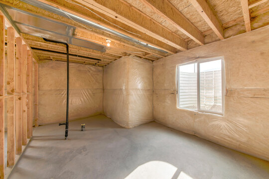 Interior of an unfinished basement with sliding window with window well