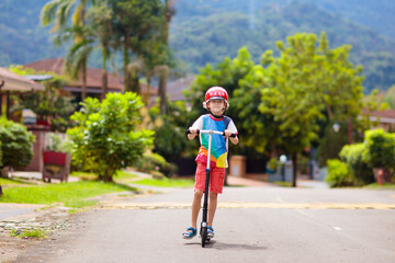 Little boy riding scooter. Kids ride kick board.