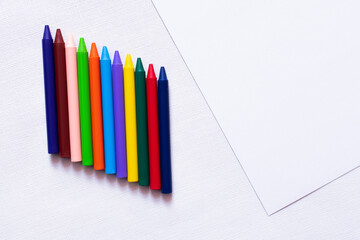 top view of colorful crayons on white textured background.