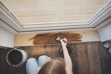 hand with a brush covers a wooden board threshold with dark impregnation (oil), top view