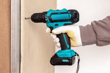 The master uses an electric screwdriver to attach the drywall to the metal profile