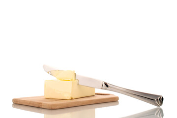 One piece of delicious butter with a metal knife on a wooden cutting board, close-up, isolated on a white background.