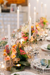 Wedding banquet. Table setting. Banquet tables are decorated with compositions of yellow flowers and protea, ranunculus on the tables are plates with napkins, glasses, candles and cutlery