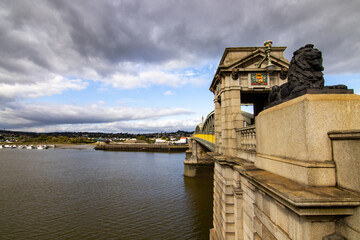 Rochester Bridge was opened in 1914, in cast iron on stone pillars, guarded by bronze lions. This image looks along the side on the bridge, over the Medway River and towards the town of Strood.   