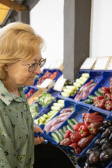 Blonde Caucasian woman concentrated in the vegetables that she is shopping to choose the best ones.