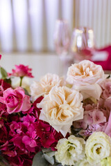 Elegant banquet table set with glasses decorated with gold, lit candles and pink flowers