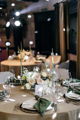 Banquet table is decorated with plates, cutlery, glasses, candles and flower arrangements. Wedding decor