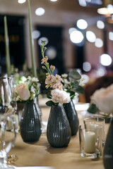 Banquet table is decorated with plates, cutlery, glasses, candles and flower arrangements. Wedding decor