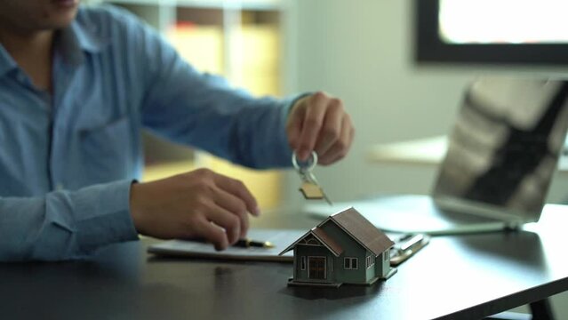 Real estate house concept laid out in front of a young man pursuing contracts for sale and rent.