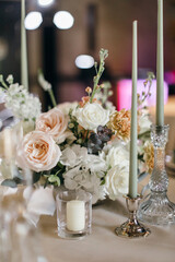 Banquet table is decorated with plates, cutlery, glasses, candles and flower arrangements. Wedding decor