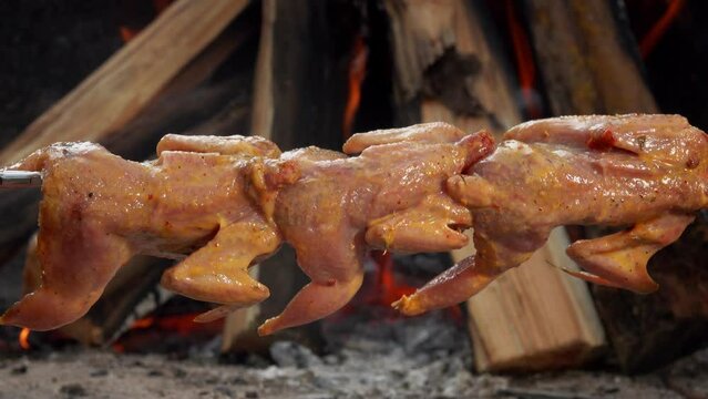 Close-up of the raw quails on the skewer placed on the background the open fire