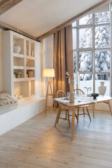 cozy warm home interior of a chic country chalet with a huge panoramic window overlooking the winter forest. open plan, wood decoration, warm colors and a family hearth