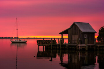 Red morning sky over Roanoke Sound from along the boardwalk at the Manteo waterfront park in North...