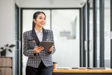 Smiling Happy Asian businessman standing and using tablet in an office